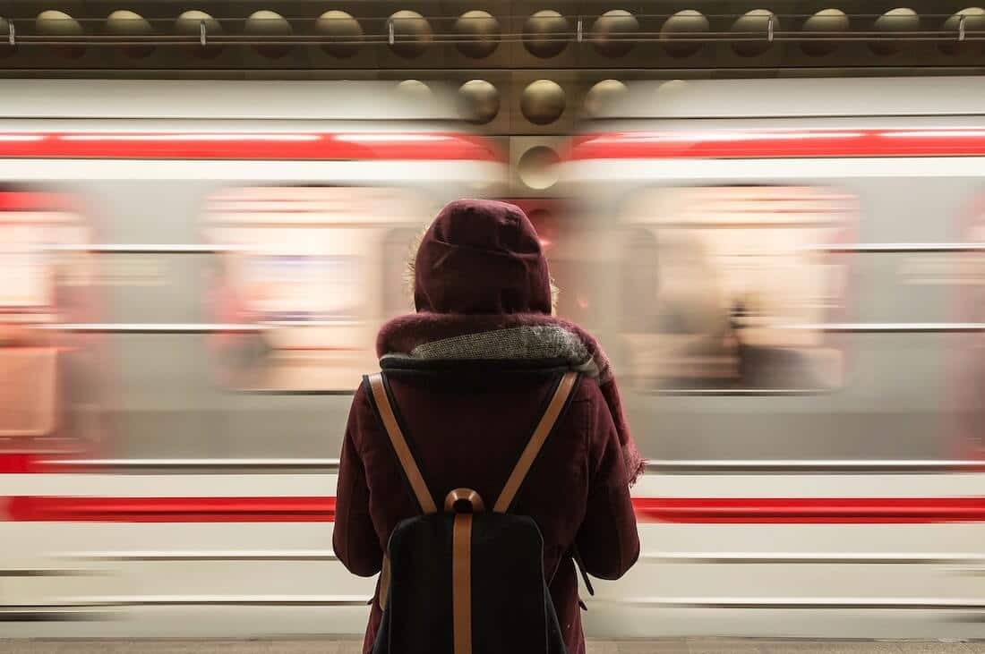Picture of woman seeing a train pass at high speed at a station.